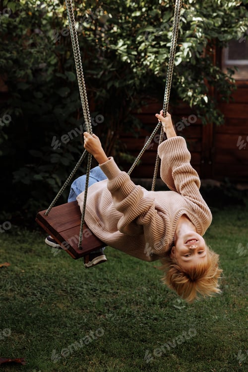 Preview: A young girl is swinging on a swing in a backyard