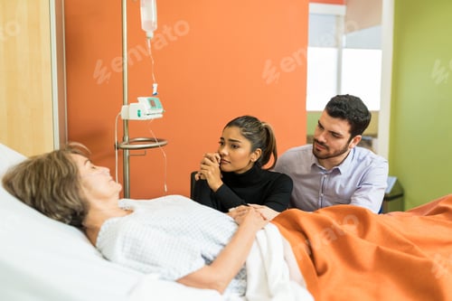 Preview: Tensed Couple Looking At Senior Mother In Hospital