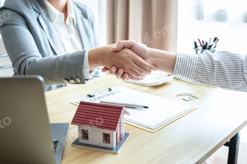 Preview: Estate agent and customers shaking hands together celebrating finished contract after signing