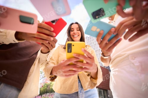 Preview: Caucasian girl looking at happy cell phone. Low angle view of group friends addicted to technology.