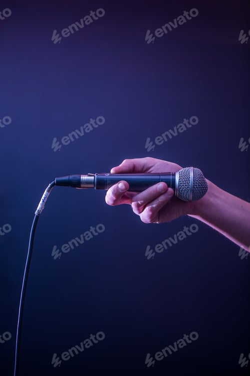 Preview: hand with microphone on a black background, the music concept, beautiful lighting on the stage