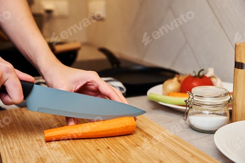Preview: Woman chopping carrot in kitchen, close up