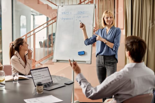 Preview: Female entrepreneur brainstorming with her coworkers while giving them presentation in the office.