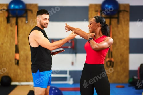 Preview: Personal trainer guiding a female client performing stretching exercises in a gym