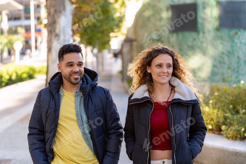 Preview: Happy multi ethnic couple walking down the street in autumn