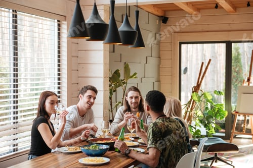Preview: Group of happy friends sitting and eating on the kitchen