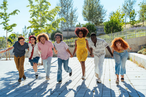 Preview: Multiethnic group of young friends meeting and having fun outdoors