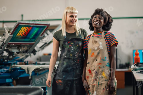 Preview: Interracial female graphic industry workers at printing shop smiling.