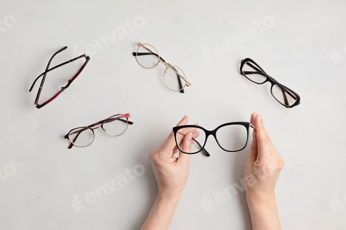 Preview: Woman hand holding eyeglasses. Optical store, glasses selection, eye test, vision examination at