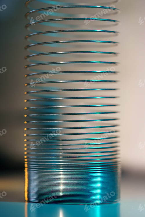 Preview: Closeup of coiled metal spring with sufficiently high strength and elastic properties in neon light