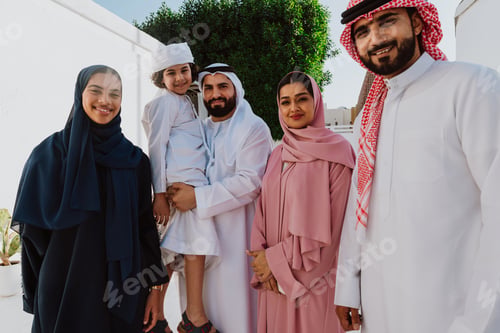 Preview: Emirati family standing together smiling in traditional attire