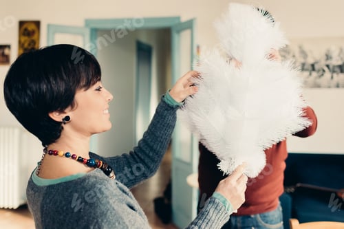 Preview: Young couple at home decorating xmas tree