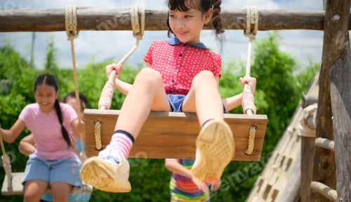 Preview: Childrens having fun swinging on a swing on a clear day