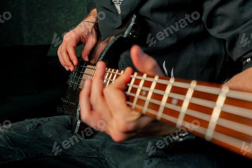 Preview: close up in the equipment of a recording room handsome man with a beard and tattoos plays an