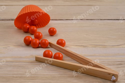 Preview: a Montessori game. Red balls with wooden tweezers.