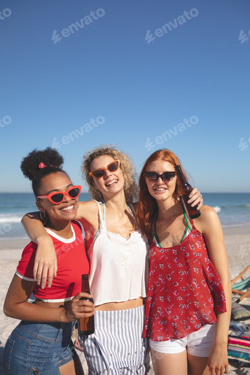 Preview: Portrait of group of young diverse female friends standing together on the beach