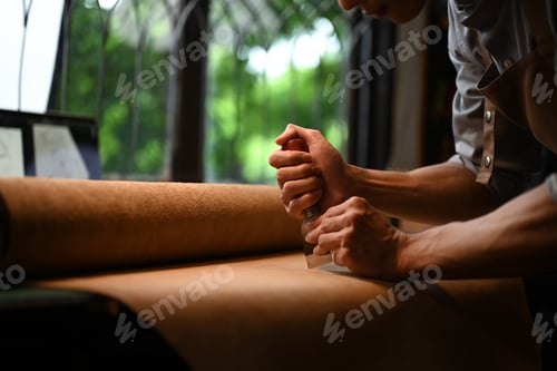 Preview: Leathersmith or leather craftsman carefully cutting pattern in his workshop