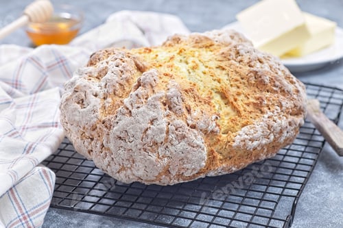 Preview: Freshly baked soda bread on cooling rack with butter and honey in the background, horizontal