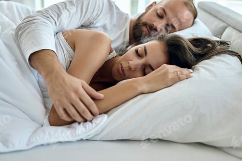 Preview: Young loving couple sleeping on a bed.