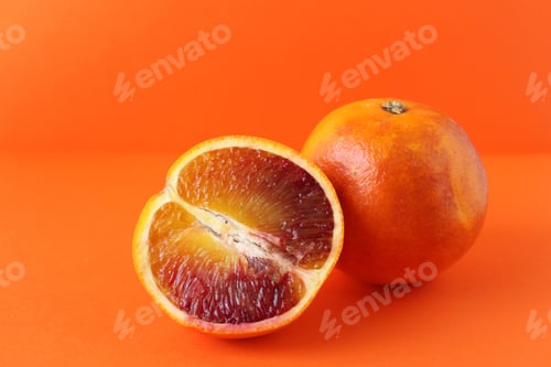 Preview: Bright orange background with whole and halved blood oranges