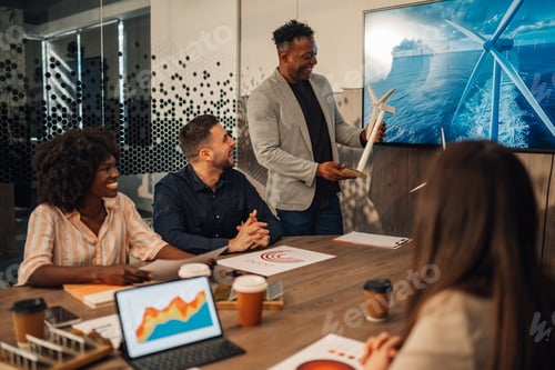 Preview: Smiling interracial businessman with windmill having seminar with team