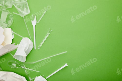 Preview: top view of disposable plastic cups, forks, spoons and cardboard containers on green background