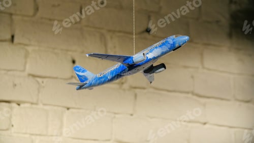 Preview: Homemade airplane in the room. On the background of stone wall hanging toy airplane on a rope, the