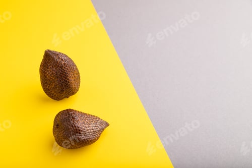 Preview: Salak or snake fruit on gray and yellow pastel background. Side view, copy space.