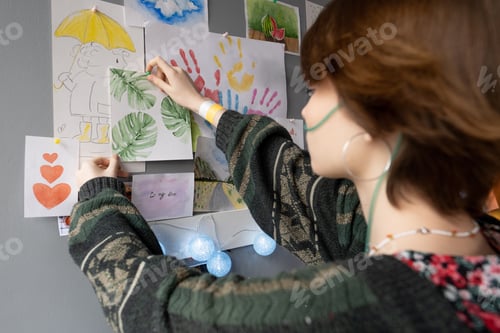 Preview: Teenage female patient of hospital hanging drawing of green leaves on wall