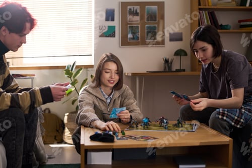 Preview: Smiling Teen Girl Playing Board Game with Friends