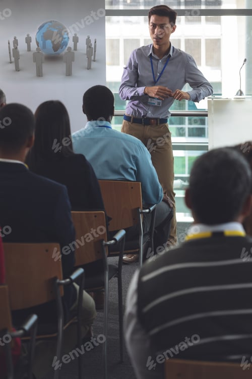 Preview: Young businessman speaking to business professionals sitting at seminar in office