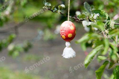 Preview: Decorative Easter egg hanging from the tree branches outdoors
