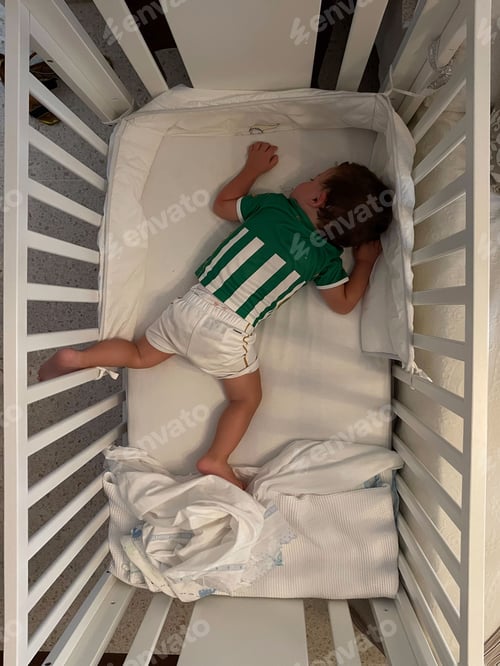 Preview: Vertical top view of a male baby sleeping on its stomach in a crib