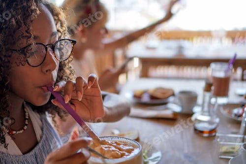 Preview: Young woman enjoying breakfast with friends during trip