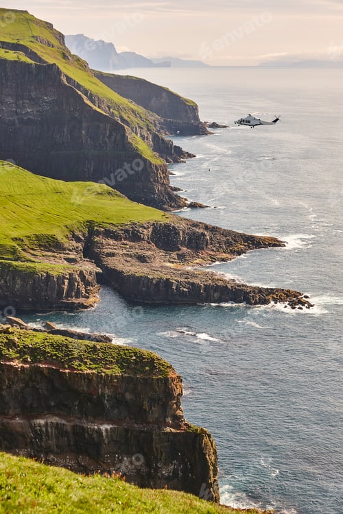 Preview: Helicopter flying over mykines atlantic cliffs in Faroe islands. Transportation