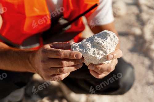 Preview: Geologist or miner examining white rocks in open quarry