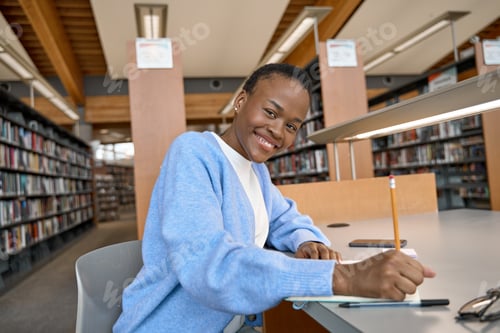 Preview: Happy African girl college student writing in notebook in library. Portrait.