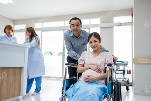Preview: Portrait of Asian husband taking care of pregnant woman in wheelchair.