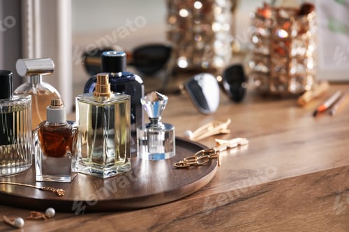 Preview: Bottles of different perfumes and accessories on wooden table, closeup. Space for text
