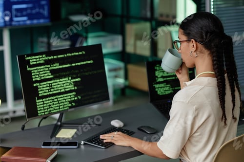 Preview: Female IT Programmer Drinking Tea while Using Computer for Writing Code in Office