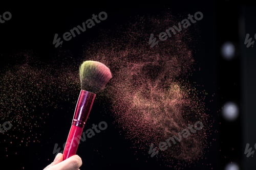 Preview: Partial view of female hand holding make-up brush with powder explosion on black
