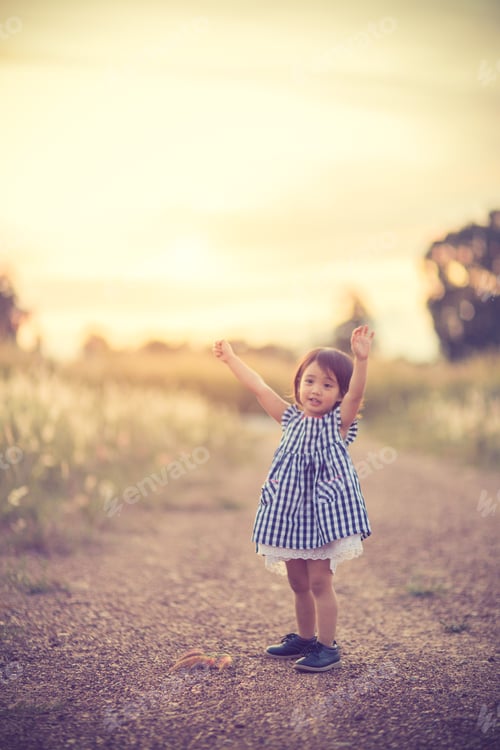 Preview: Happy cute kid in a field playing with natural spikes at summer sunset.