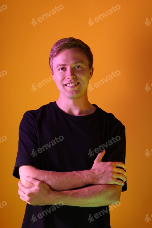 Preview: Portrait of smiling man in neon lights against orange background