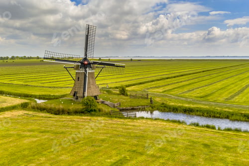 Preview: Old wooden windmill in green agricultural grassland