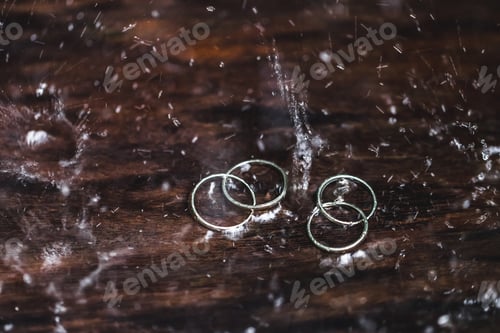 Preview: Double white gold wedding rings under water drops splash close up. Studio macro shot