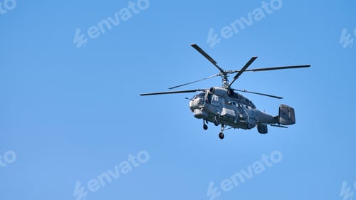 Preview: Navy helicopter flying against blue sky background, copy space. One rotary wing aircraft, side view