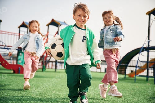 Preview: Holding soccer ball in hand, running. Kids are having fun on the playground