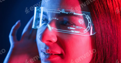 Preview: In futuristic eyewear. Young beautiful woman is indoors in the studio illuminated by neon light
