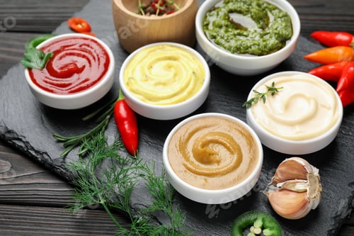 Preview: Different sauces and herbs on wooden table, closeup