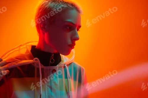 Preview: Young short haired woman looking away in bright neon studio
